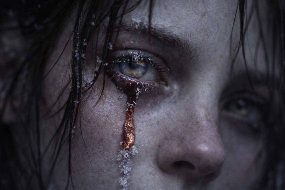 Red tear freezing on Maris's cheek, the damaged eye bleeding